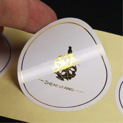 Custom die cut gold foil sticker with glossy lamination on 80 GSM material, featuring shiny gold accents and vibrant print for premium branding.