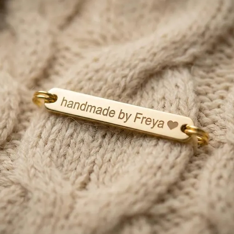 Luxury metal garment labels with custom engraving for apparel and accessories.
