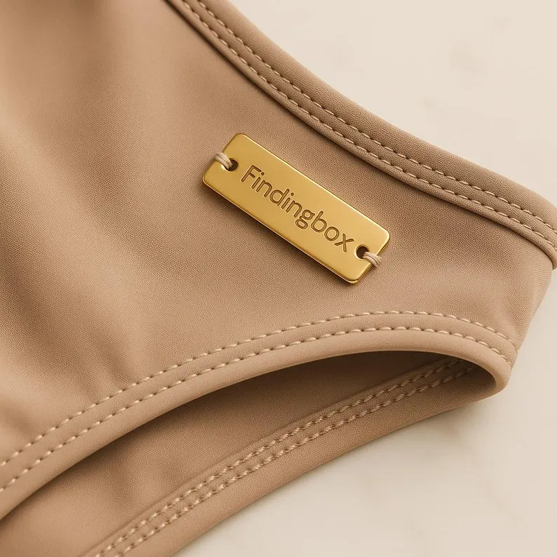 Personalized metal nameplates in gold, silver, and black for garment branding.