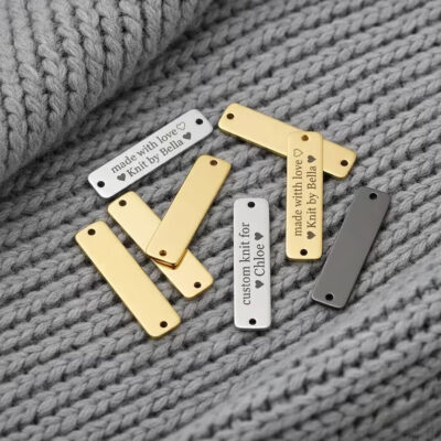 Custom engraved metal labels in gold, silver, and black finishes for clothing, garments, and handmade products.